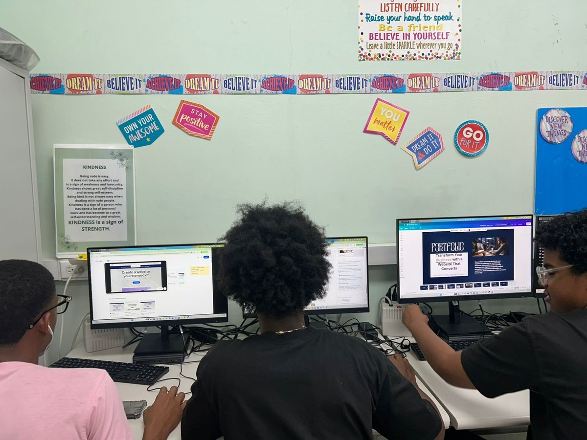 Students working at computers in a classroom with motivational posters and colorful decorations on the walls